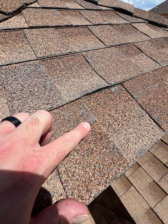 Close-up of hail bruising and granule loss on an old shingle