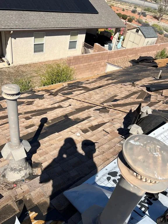 Old tan shingles being torn off the roof deck