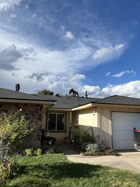 Front of the same home with the new dark gray roof as the crew finishes the ridge