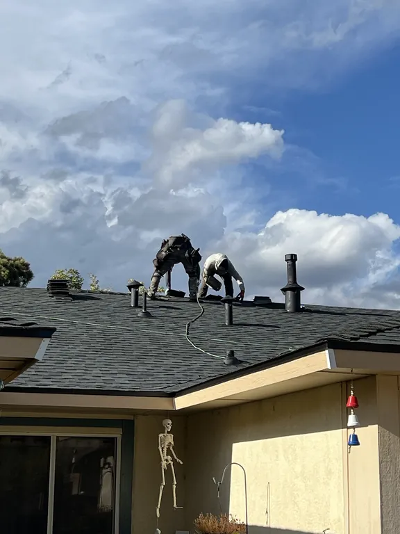 Two Timberwolf roofers installing ridge cap on the final day