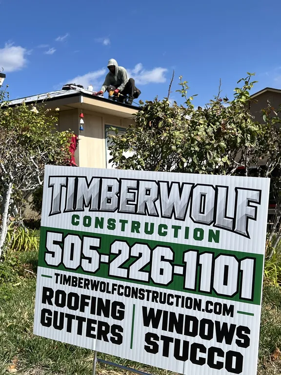 Timberwolf Construction yard sign in front of the home while a roofer works on the roof