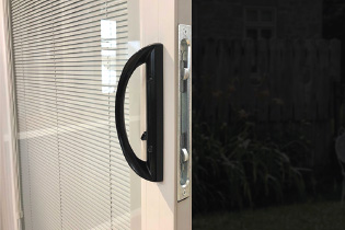Close-up of a sliding patio door handle with blinds between the glass