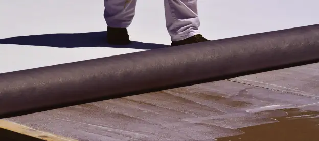 Fleece-back membrane being rolled into low-rise foam adhesive