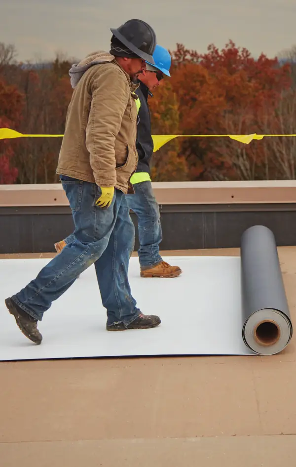 Roofing crew rolling out GAF EverGuard PVC fleece-back membrane