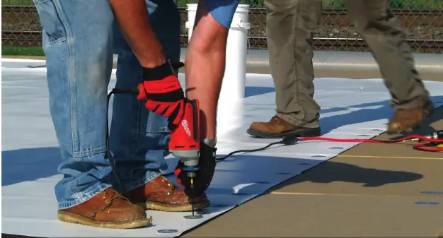 Installer fastening TPO membrane to the roof deck at the seam