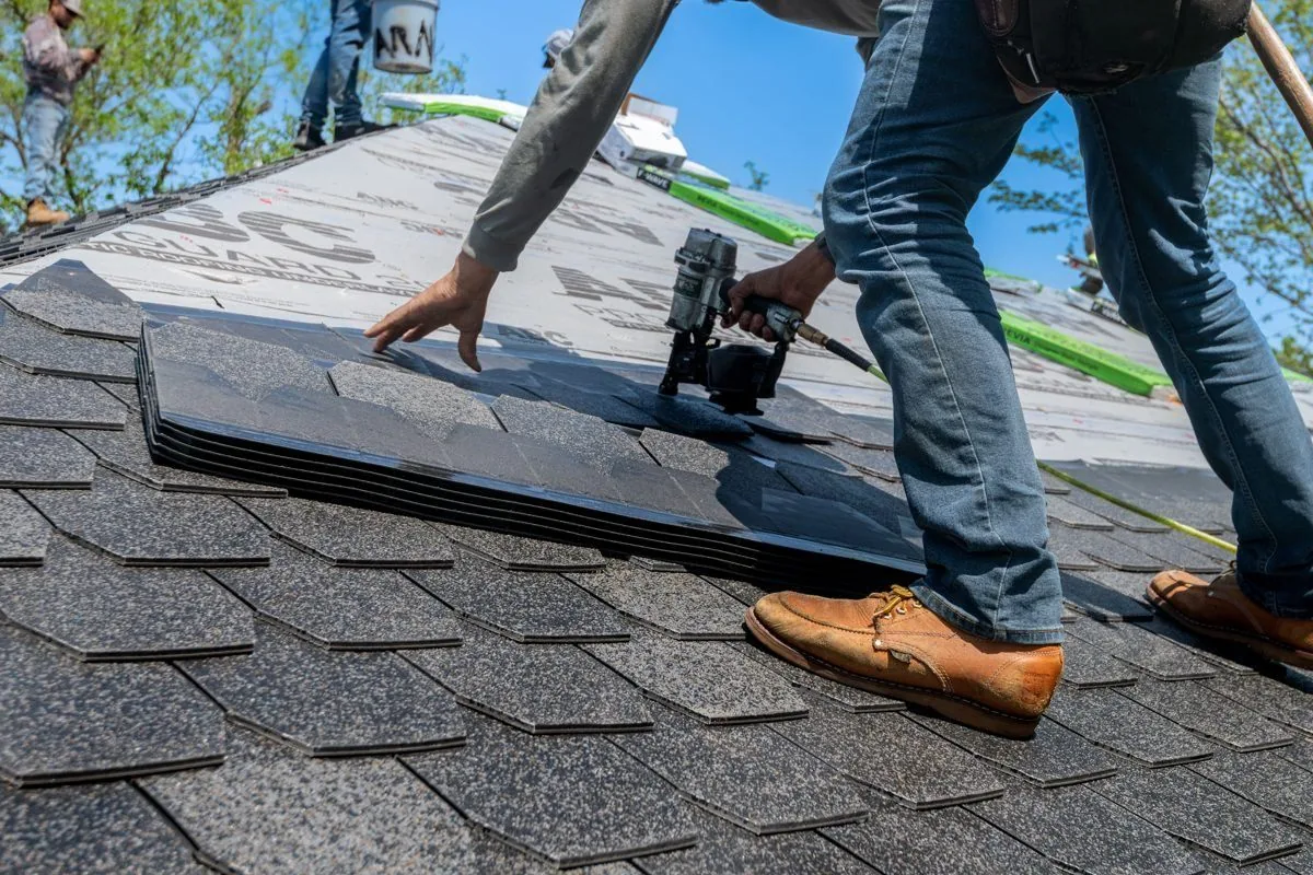 Roofer performing a repair on an asphalt shingle roof