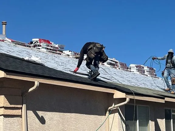 Roofer installing new charcoal architectural shingles over GAF Tiger Paw underlayment