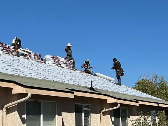 Timberwolf roofing crew working on GAF Tiger Paw underlayment with shingle bundles staged on the roof