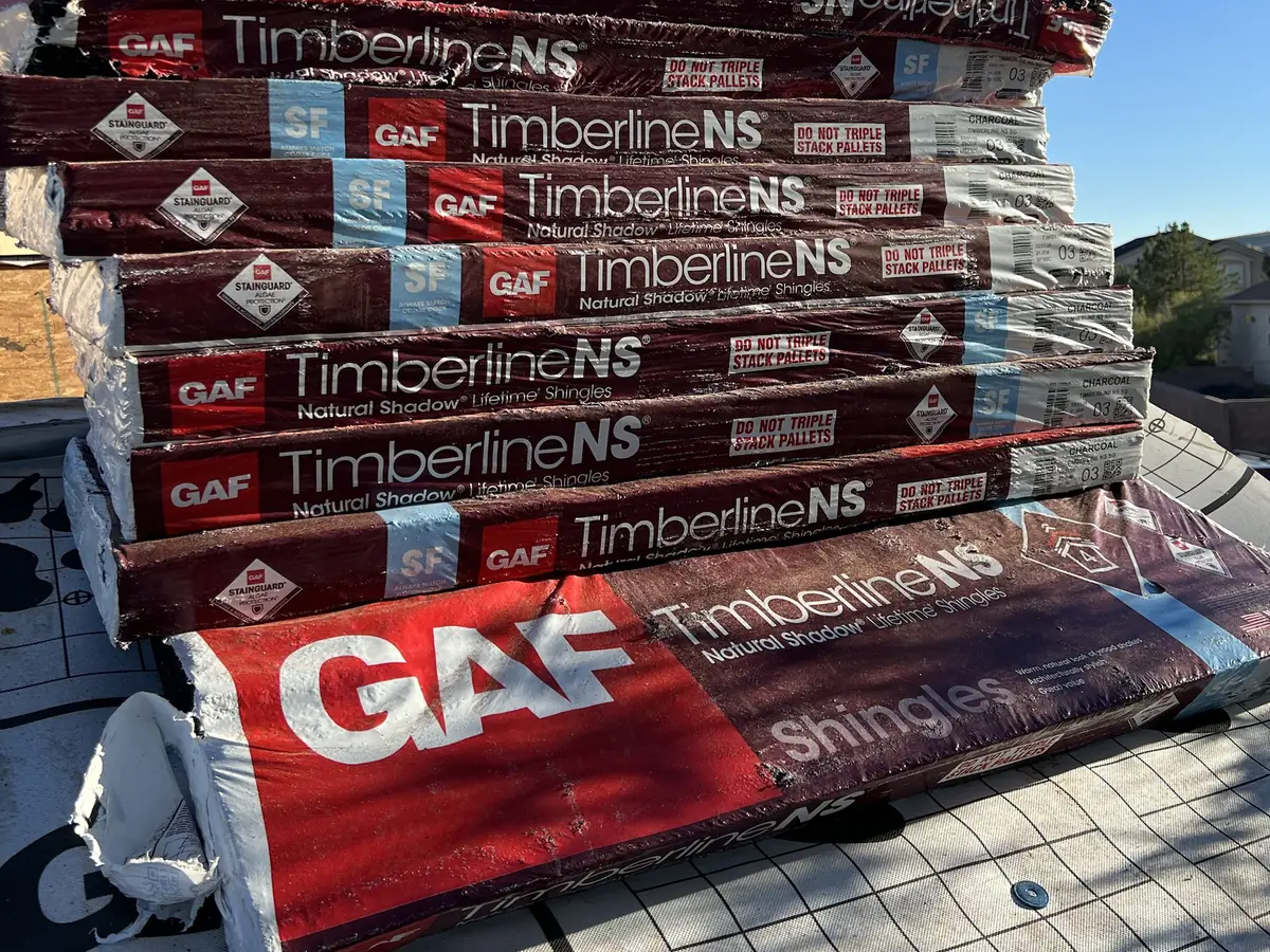 Stack of GAF Timberline NS Charcoal shingle bundles on the roof