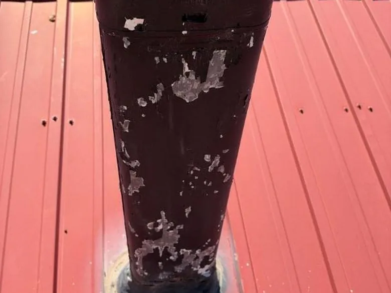 Weathered flue pipe and flashing on a metal roof
