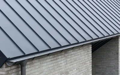 Dark gray A-Lock standing seam metal roof with concealed fasteners at a brick-wall eave