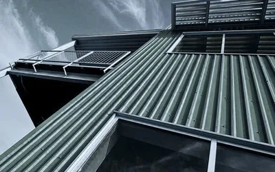 Dark green PBU ribbed metal panels used as siding on a modern multi-level building