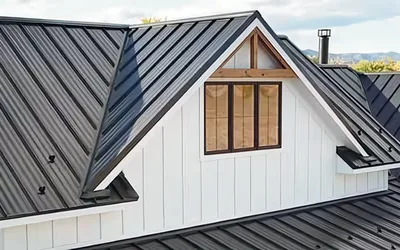 Charcoal Zia Rib exposed-fastener metal roof on a white board-and-batten farmhouse with a gable dormer